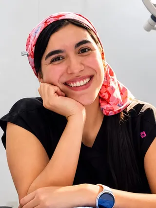 Retrato de la Dra. Cristina Reyes Mejía sonriendo, con pañuelo rosa de quirófano