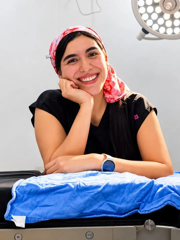 Retrato de la Dra. Cristina Reyes Mejía sonriendo, con pañuelo rosa de quirófano